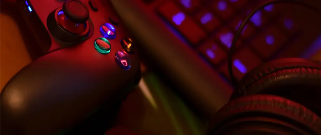 Een gamecontroller, een oplichtende muis en een koptelefoon op een bureau, verlicht door felle neonlichten, die een hightech, meeslepende gamingopstelling uitstralen.